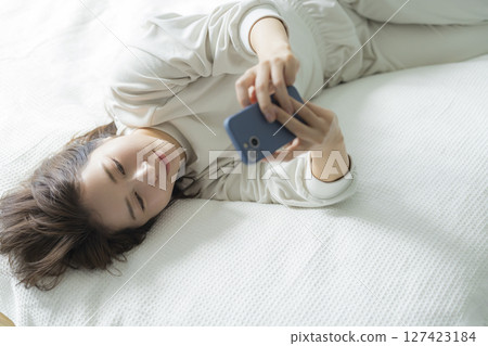 A woman watching a smartphone in bed A woman watching a smartphone in bed 127423184