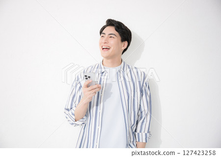 一名身穿襯衫、手持智慧型手機的男子 一名身穿襯衫、手持智慧型手機的男子 127423258
