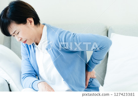 Middle-aged woman feeling back pain Middle-aged woman feeling back pain 127423381
