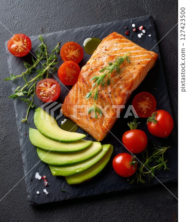 Grilled salmon with avocado and cherry tomatoes on slate board. 127423500