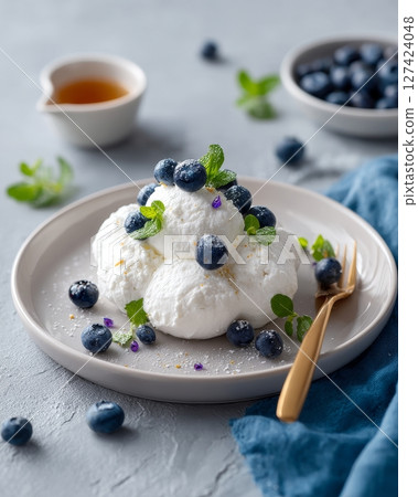 Whipped cream with blueberries and mint on plate with spoon. Whipped cream with blueberries and mint on plate with spoon. 127424048
