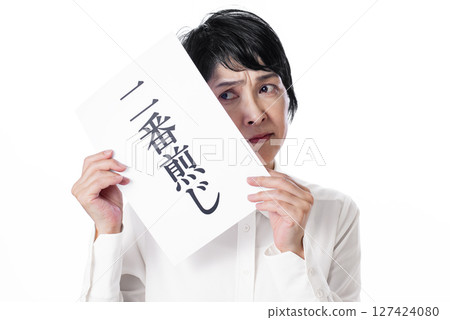 A middle-aged woman frowning as she holds a piece of paper with the word "copycat" written on it A middle-aged woman frowning as she holds a piece of paper with the word "copycat" written on it 127424080
