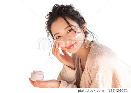 一位日本年輕女子在臉頰上塗抹護膚霜（美容、保濕、自我照顧） 127424671