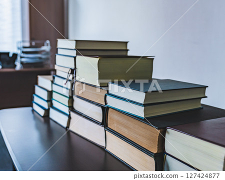 There are a lot of technical books piled up in the room. 127424877