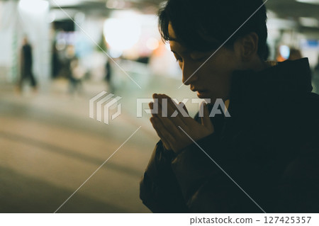 A man in his 20s blowing on his hands in the cold 127425357