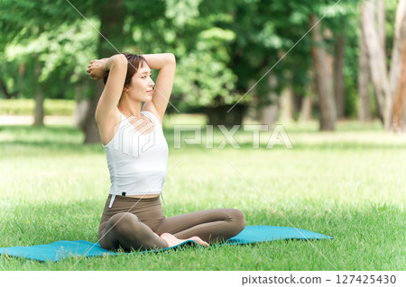 A female yoga instructor doing yoga, yoga class, pilates in the park or forest 127425430