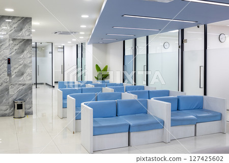 Row of comfortable couches in waiting room for patients with doctor appointments in a modern healthcare clinic or hospital 127425602