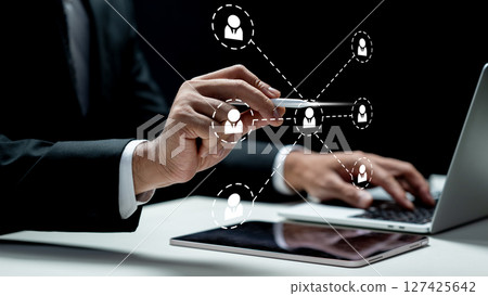 Businessman using a laptop while touching the connected people icon on the tablet screen. Technology innovation on a virtual screen. Concept of public relations Businessman using a laptop while touching the connected people icon on the tablet screen. Technology innovation on a virtual screen. Concept of public relations 127425642