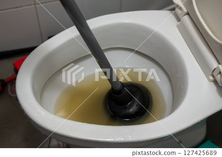 hand is using an air pump to solve a clogged toilet. 127425689
