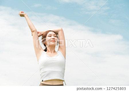 穿著瑜珈服的女人在藍天下伸展（運動、深呼吸、日光浴、提神、緩解壓力） 127425803