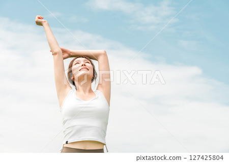 穿著瑜珈服的女人在藍天下伸展（運動、深呼吸、日光浴、提神、緩解壓力） 127425804