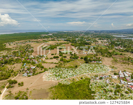 Tropical island with small town near in coastline. Blue sky and clouds. Mindanao, Philippines. 127425884