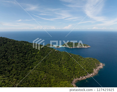 Tropical island with dense greenery surrounded by clear blue ocean under a bright sky. Thailand, Koh Tao. Tropical island with dense greenery surrounded by clear blue ocean under a bright sky. Thailand, Koh Tao. 127425925
