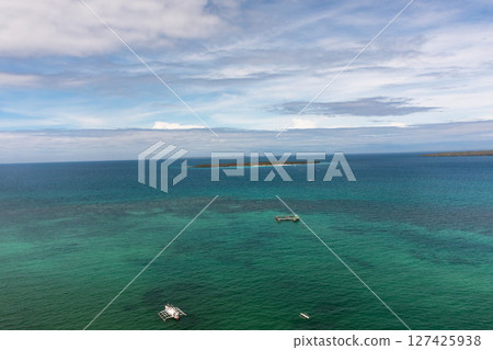 Tropical seascape, island with beach surrounded by blue sea. Boat over the sea. Blue sky and clouds. Bantayan, Cebu. Philippines. Tropical seascape, island with beach surrounded by blue sea. Boat over the sea. Blue sky and clouds. Bantayan, Cebu. Philippines. 127425938