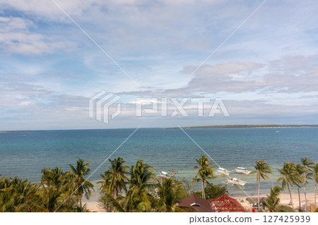 Beach view from above, palm trees and ocean waves crashing on white sands. Baigad Lagoon Beach. Bantayan Island, Cebu, Philippines. 127425939