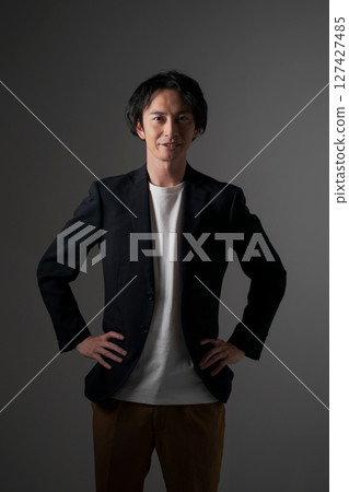 A young man wearing a black jacket (black background) 127427485