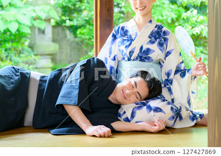 A scene of a man and woman in yukata sitting side by side on the veranda, exchanging gentle smiles and enjoying a relaxing summer afternoon. A scene of a man and woman in yukata sitting side by side on the veranda, exchanging gentle smiles and enjoying a relaxing summer afternoon. 127427869