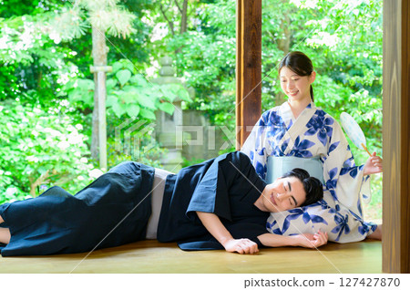 Men and women in yukatas sit on the veranda and exchange conversations, spending a relaxing time together in the quiet summer. 127427870