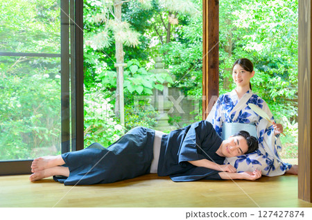 一個夏日場景：一個男人躺在陽台上，一個女人穿著浴衣，緊緊依偎在一起，度過安靜的時光 127427874