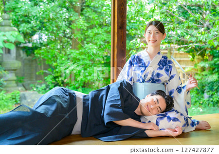 Men and women in yukatas relaxing on the veranda in summer with smiles on their faces, spending time together peacefully in the soft light. 127427877