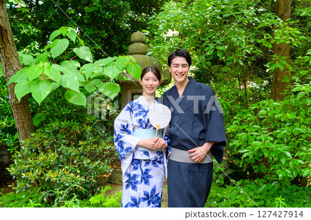 A summer scene of couples in yukata standing side by side in a Japanese-style garden, enjoying the cool weather and smiling happily at the camera A summer scene of couples in yukata standing side by side in a Japanese-style garden, enjoying the cool weather and smiling happily at the camera 127427914
