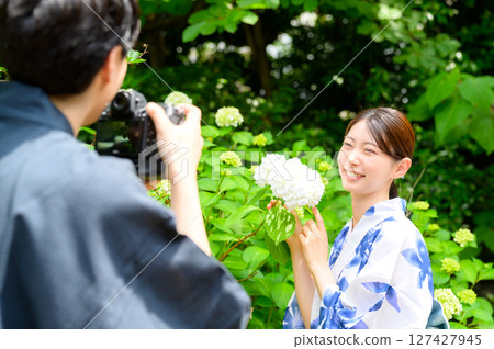 A summer snapshot portrait of a man taking a photo of a smiling woman in a yukata in a garden A summer snapshot portrait of a man taking a photo of a smiling woman in a yukata in a garden 127427945