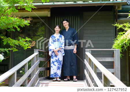一幅充滿情感的畫像，描繪了一位身著浴衣的男子和一位身著浴衣的女子並肩站在日式旅館的陽台上，度過一個寧靜的夏日時光 127427952