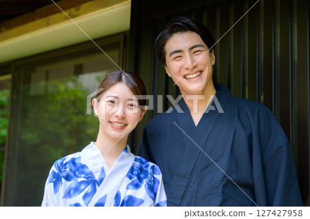 A commemorative summer portrait of a man and woman in yukata smiling brightly while standing close together on the veranda of a Japanese-style inn A commemorative summer portrait of a man and woman in yukata smiling brightly while standing close together on the veranda of a Japanese-style inn 127427958