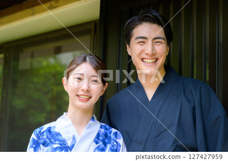 一張照片中,身穿清爽浴衣的男女站在日式房屋前,面帶微笑,展現夏日的時光。 一張照片中,身穿清爽浴衣的男女站在日式房屋前,面帶微笑,展現夏日的時光。 127427959