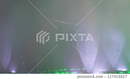 Water Fountain Lights Night Show: Atmospheric nighttime water feature display showcasing illuminated jets. 127428827