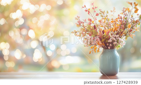 Elegant autumn floral arrangement in warm, muted tones against a bokeh background of golden light. 127428939