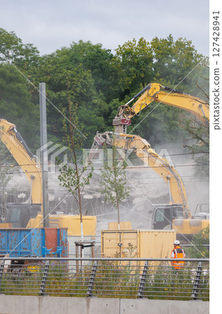 Close-up view of crumbling bridge structure demolition in Magdeburg Damaschkeplatz exposed steel rebar falling concrete chunks. Rubble piles and demolition machinery emphasize destruction progress Close-up view of crumbling bridge structure demolition in Magdeburg Damaschkeplatz exposed steel rebar falling concrete chunks. Rubble piles and demolition machinery emphasize destruction progress 127428941