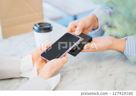 A woman's hand purchasing coffee at a store by touch payment on her smartphone A woman's hand purchasing coffee at a store by touch payment on her smartphone 127429180