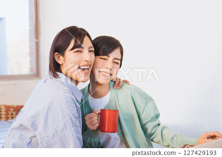 兩位 30 多歲的女性朋友看著鏡頭，微笑著，互相扶著肩膀 127429193