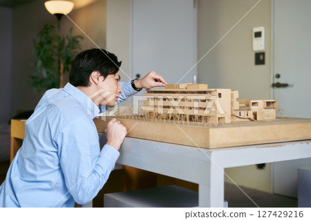 Architecture students looking at a model of a building and simulating the actual building Architecture students looking at a model of a building and simulating the actual building 127429216