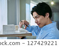 One Asian male designer looking at architectural models and thinking about building designs 127429221