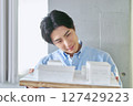 Smiling male college student studying building design by looking at a model in the architecture department of the university's engineering faculty 127429223