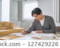 A male college student studying at the architecture department of an engineering university, writing blueprints for urban planning next to an architectural model 127429226