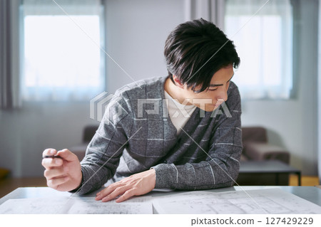 A male interior coordinator thinking about interior design while looking at a building blueprint A male interior coordinator thinking about interior design while looking at a building blueprint 127429229