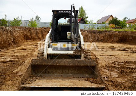 Excavator in the excavation at the construction site during the day Excavator in the excavation at the construction site during the day 127429490