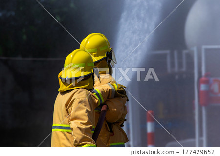 Firefighters in Action Spraying Water to Stop the Fire 127429652