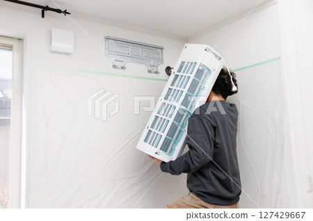 A worker installing an air conditioner A worker installing an air conditioner 127429667