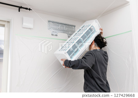 A worker installing an air conditioner A worker installing an air conditioner 127429668