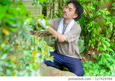 一名男子正在仔細檢查石燈籠上的雕刻，準備在夏季工作開始前進行維護。 127429766