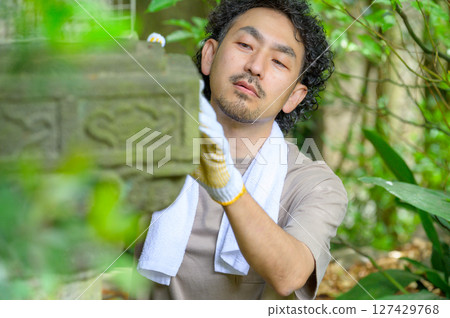 一名男子在花園裡安靜地工作，凝視著燈籠的表面，用手輕輕觸摸它以檢查其狀況 127429768