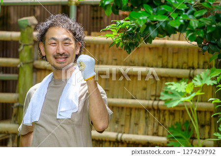 明亮的夏日花園肖像，一位男子完成任務後微笑著舉起拳頭，充滿成就感 127429792
