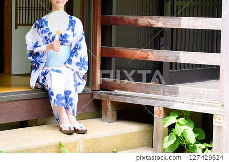 A scene of a woman in a yukata sitting quietly on a Japanese-style veranda, enjoying the summer time with a calm expression on her face. A scene of a woman in a yukata sitting quietly on a Japanese-style veranda, enjoying the summer time with a calm expression on her face. 127429824