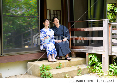 旅館裡寧靜的夏日景象，身著浴衣的男女並肩坐在陽台上，一起度過悠閒的時光 127429831