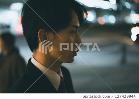 A young male business person rushing home at night 127429944
