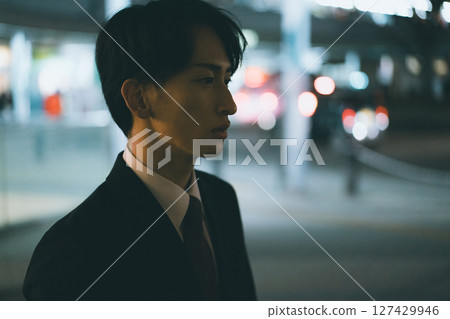 A young male business person rushing home at night 127429946